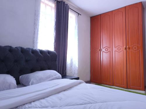 1 Schlafzimmer mit 2 Betten und einem großen Holzschrank in der Unterkunft Trm homes in Nairobi