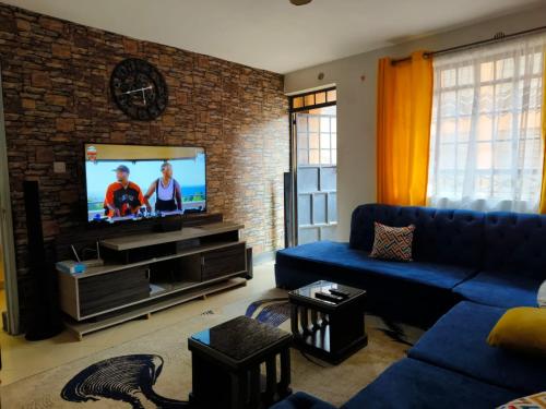 ein Wohnzimmer mit einem blauen Sofa und einem TV in der Unterkunft Trm homes in Nairobi