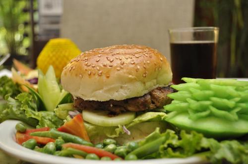 a plate of food with a burger and salad and a glass of drink at The Residency Hotel in Lahore
