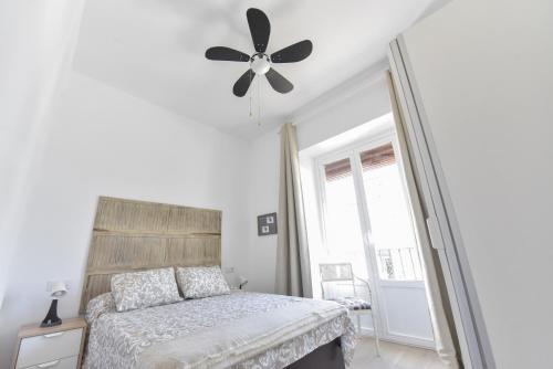 1 dormitorio con 1 cama y ventilador de techo en Apartamentos Gran Vía, en Aracena