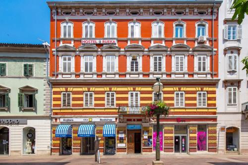 a large orange building with white windows on a street at Molo Longo - Downtown Apartments in Rijeka