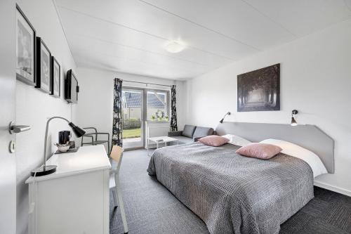 a white bedroom with a bed and a desk at Skovdal Kro in Jelling