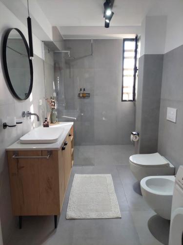 a bathroom with a sink and a toilet and a mirror at BeHOME in Tirana