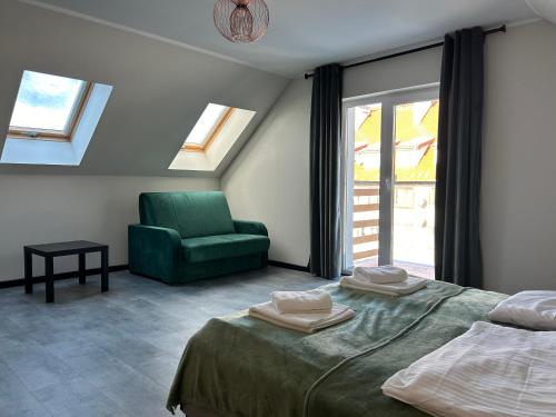 a bedroom with two beds and a green chair at Apartamenty Antonio 2 in Kudowa-Zdrój