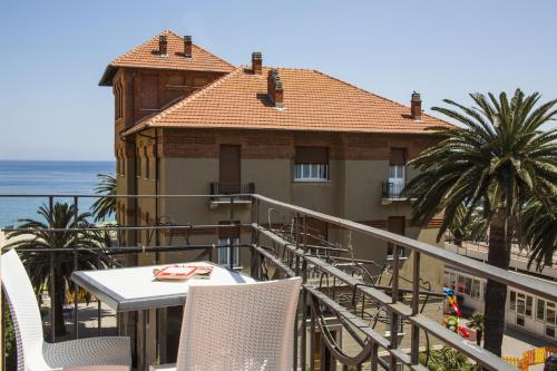 un balcón con mesa y sillas y un edificio en Hotel Mimosa, en Spotorno