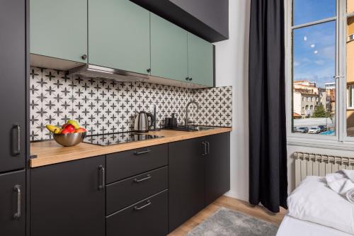 a kitchen with black cabinets and a bowl of fruit on the counter at Molo Longo - Downtown Apartments in Rijeka