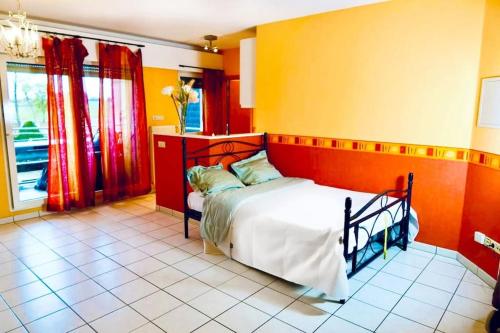 1 dormitorio con 1 cama con paredes de color naranja y amarillo en Studio - Thermes de Mondorf en Mondorf-les-Bains