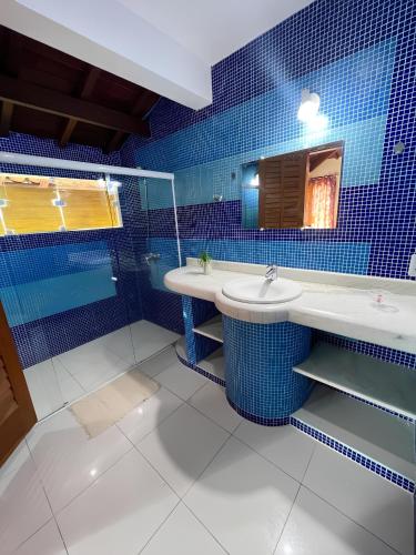 uma casa de banho em azulejos azuis com 2 lavatórios e um espelho. em Pousada Casa Mucugê em Porto Seguro