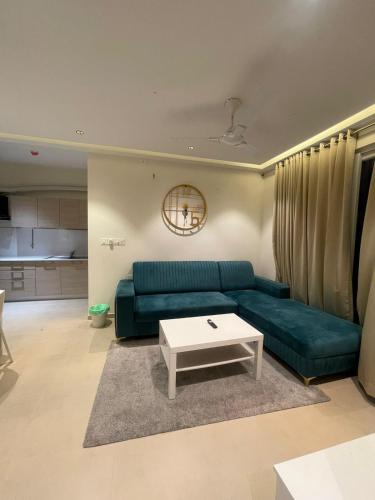 sala de estar con sofá verde y mesa en Hobbit - A sophisticated 2 bhk In Bharathiya city en Bangalore