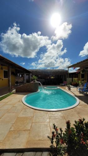 a swimming pool with a fountain in a yard at Pousada Céu Azul in São Miguel do Gostoso