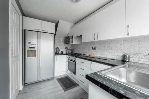 a white kitchen with a sink and a refrigerator at Contractors - Family - City Centre - NEC in Birmingham