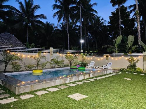 a backyard with a swimming pool with lights and a lawn at Birbeck Lodge in Bulusan