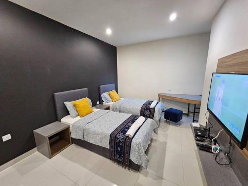 een kamer met 2 bedden en een flatscreen-tv bij Kozi Square New SGH Cozy Home 3F in Kuching