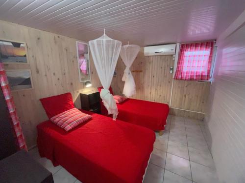 a bedroom with two red beds and a chandelier at MARINA DU MARIN in Le Marin