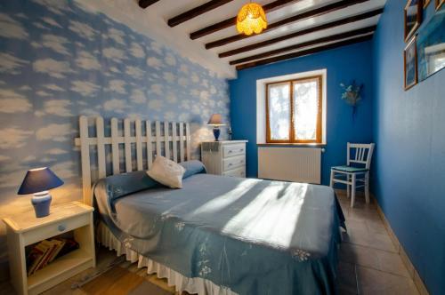 Schlafzimmer mit blauen Wänden, einem Bett und einem Fenster in der Unterkunft Les colchiques in Racines