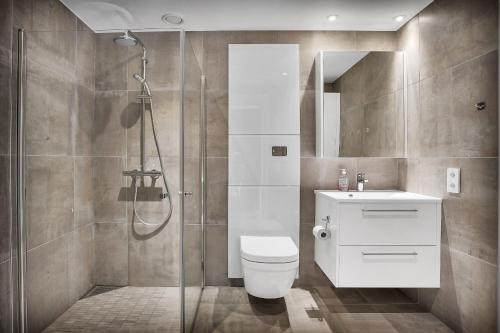 uma casa de banho com um chuveiro, um WC e um lavatório. em TA Vervet Apartment Hotel em Tromsø