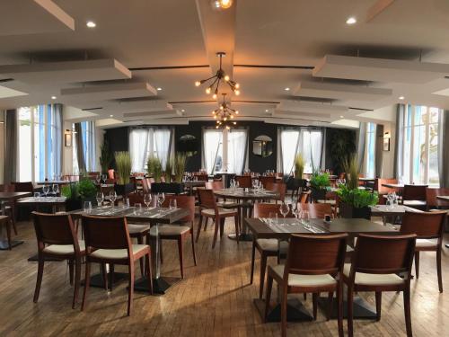 a dining room with tables and chairs and a chandelier at LOGIS Hôtel & Restaurant - Les Bords de Seine in La Roche-Guyon