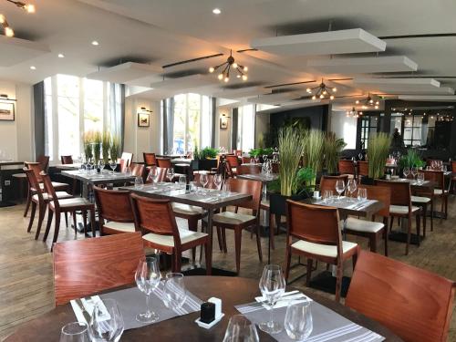 a dining room with tables and chairs with wine glasses at LOGIS Hôtel & Restaurant - Les Bords de Seine in La Roche-Guyon