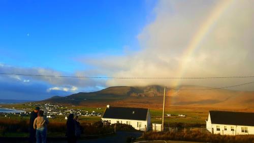 un arco iris en el cielo con gente mirando una montaña en Sona Baile Home Stay, en Dooagh