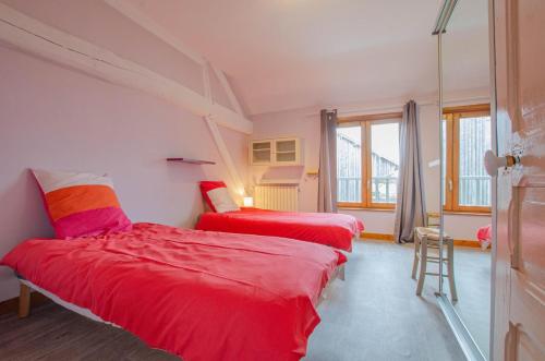 2 Betten in einem Zimmer mit roter Bettwäsche in der Unterkunft La ferme du chateau in Méry-sur-Seine