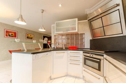 une cuisine avec des armoires blanches et un comptoir noir dans l'établissement Le gros raisin, à Troyes