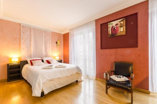 a bedroom with a large bed and a chair at Le gros raisin in Troyes