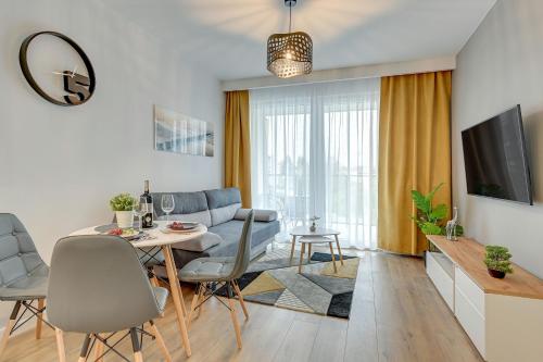 - un salon avec une table, des chaises et un canapé dans l'établissement Comfort Apartments Kopernika, à Gdynia