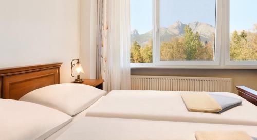2 camas en un dormitorio con 2 ventanas en Hotel Academia en Stará Lesná