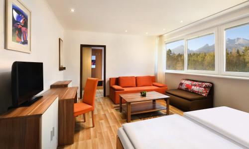 a living room with a couch chair and a television at Hotel Academia in Stará Lesná