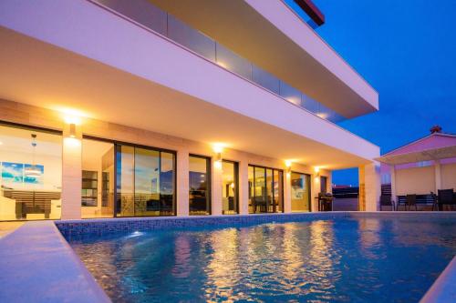 an indoor swimming pool in a house at night at Luxury Villa Eligo with private pool and sea view in Premantura