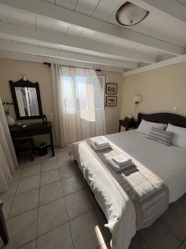 a bedroom with a large white bed and a desk at Maria's Place - Adults Only in Oia