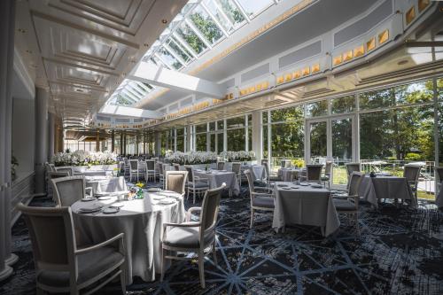 a dining room with tables and chairs and windows at Steigenberger Hotel Der Sonnenhof in Bad Wörishofen