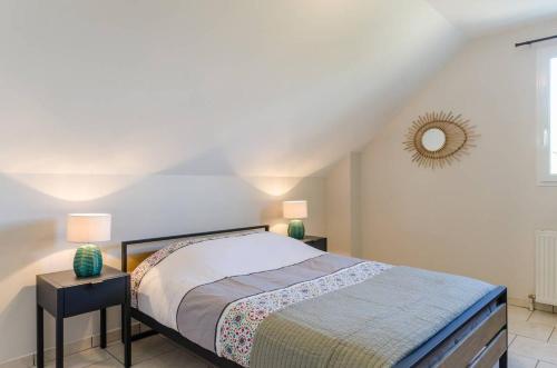 1 dormitorio con 1 cama con 2 lámparas y espejo en Les bigarreaux, en Paisy-Cosdon