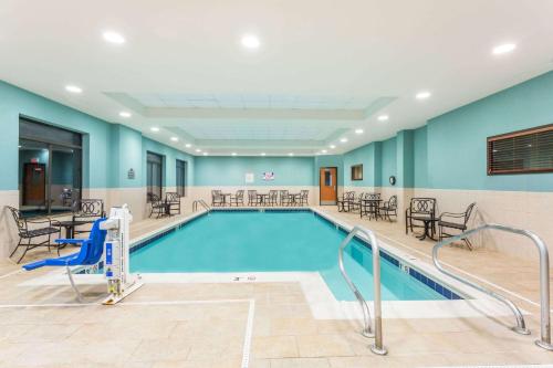 a swimming pool with tables and chairs in a building at Wingate by Wyndham Richmond Short Pump in Richmond