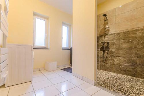y baño con ducha y suelo de baldosa. en La menuiserie du pre, en Rigny-la-Nonneuse