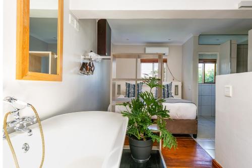 a bathroom with a bed and a sink and a tub at Camps Bay Village in Cape Town