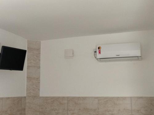 a room with a white wall with a air conditioner at Pausada do Gilmar in Ribeirão