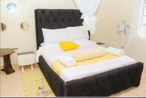 - un grand lit avec une tête de lit noire dans la chambre dans l'établissement Heavenly Homes - C, à Kakamega