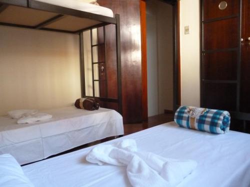 a bedroom with two beds with white sheets at Hostel Casa Mineira in Belo Horizonte