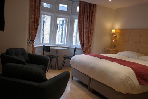 ロンドンにあるThe Alma Roomsのベッド、椅子、テーブルが備わるホテルルームです。