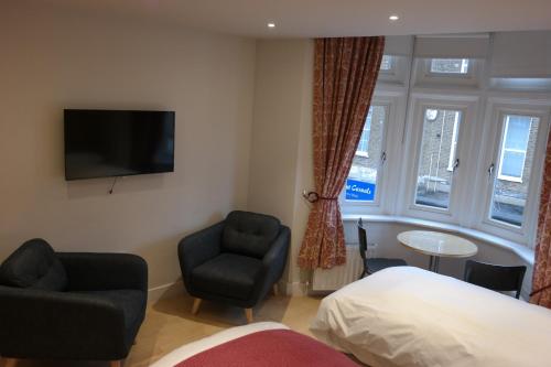 a bedroom with a bed and a chair and a television at The Alma Rooms in London