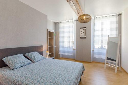 a bedroom with a bed with a blue comforter and two windows at Le saint remeau in Le Jard