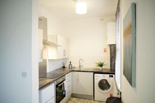 a kitchen with a washing machine and a washer at Aqua Springs, luxury 2 bed, 2 bath apartment, near Didsbury in Manchester