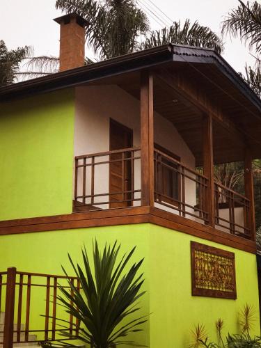 a green house with a balcony on top of it at Chalés Vani in Resende