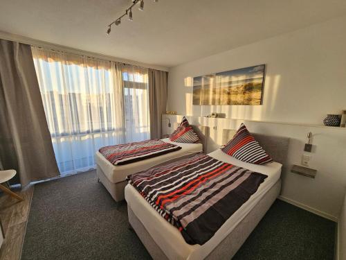 a hotel room with two beds and a window at FEWO FAUBEL Mülheim Forum City 60 m2 inclusive Garagenstellplatz in Mülheim an der Ruhr