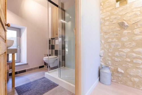Un baño con ducha de cristal y un inodoro. en La maisonnette, en Estissac