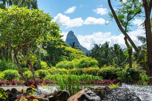 a garden with a mountain in the background at Hilton Mauritius Resort & Spa in Flic-en-Flac