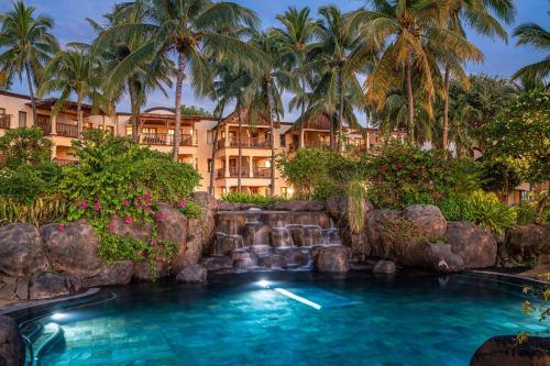 a pool in front of a resort with palm trees at Hilton Mauritius Resort & Spa in Flic-en-Flac