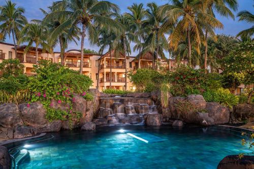 - une piscine en face d'un complexe avec des palmiers dans l'établissement Hilton Mauritius Resort & Spa, à Flic-en-Flac