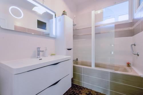 ein weißes Badezimmer mit einem Waschbecken und einer Badewanne in der Unterkunft Le messager in Pougy